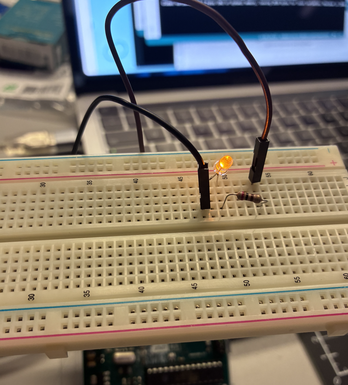 A lone LED sits on the breadboard with two jumper wires and a resistor completing the circuit.