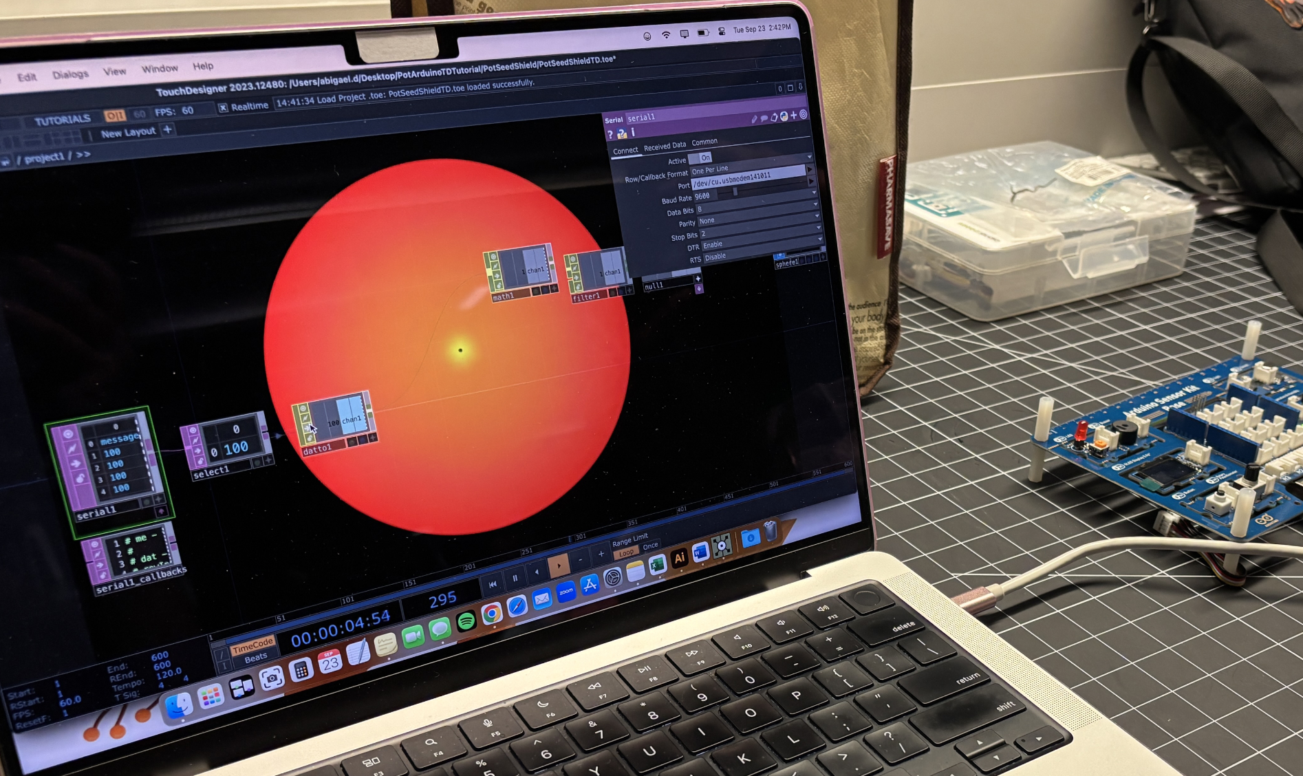 TouchDesigner displays a data visualization—a glowing orange sphere—connected to an Arduino sensor board, showing real-time serial data communication between the hardware (potentiometer) and software.